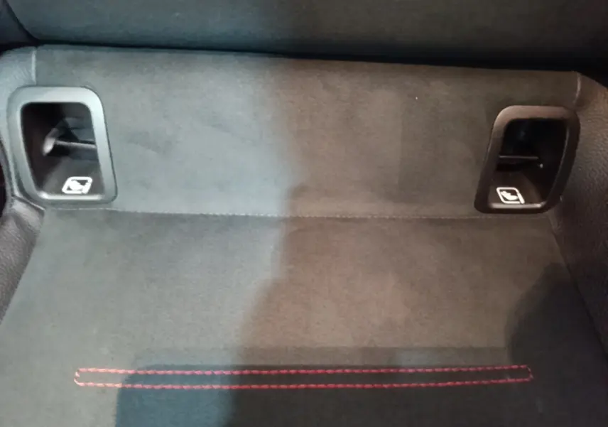 Détail du coffre avec tapis noir et deux leviers de rabattement des sièges arrière sur Mercedes CLA 200 d AMG Line.