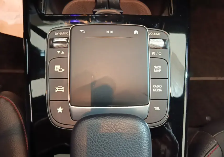 Gros plan sur la console centrale noire brillante de la Mercedes CLA 200 d AMG Line 2022 avec pavé tactile et boutons multifonctions.