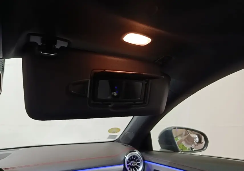 Intérieur noir de la Mercedes CLA 200 d AMG Line 2022, vue du pare-soleil avec miroir éclairé et tableau de bord éclairage bleu.