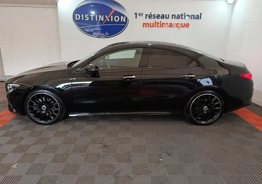 Vue de profil côté gauche d'une Mercedes CLA 200 d AMG Line noire avec jantes noires brillantes en intérieur showroom.