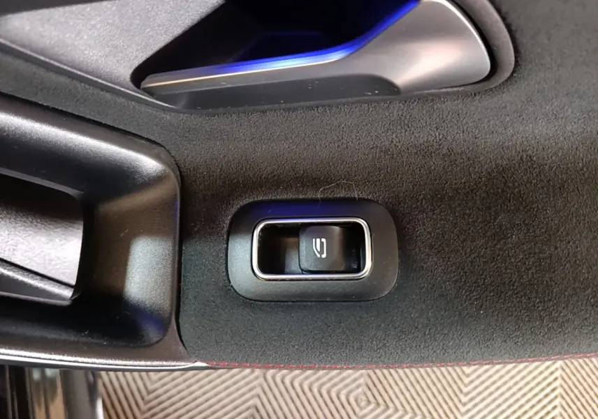 Gros plan sur le bouton de déverrouillage intérieur de la porte côté gauche d’une Mercedes CLA 200 d AMG Line noire.