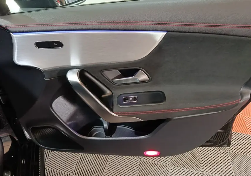 Vue intérieure du panneau de porte avant gauche noir avec surpiqûres rouges et insert aluminium brossé sur Mercedes CLA 200 d AMG Line 2022.