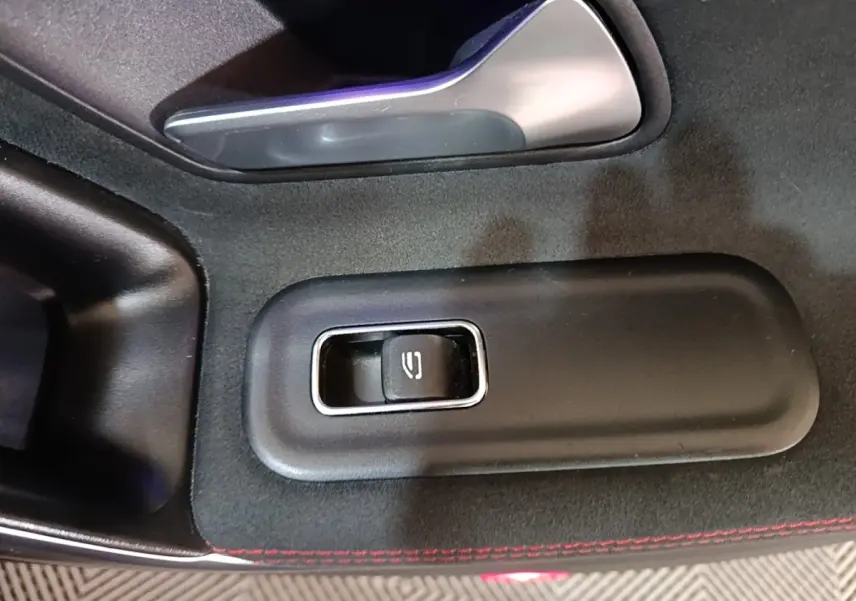 Gros plan sur le bouton de lève-vitre électrique, intérieur noir avec surpiqûres rouges d'une Mercedes CLA 200 d AMG Line 2022.