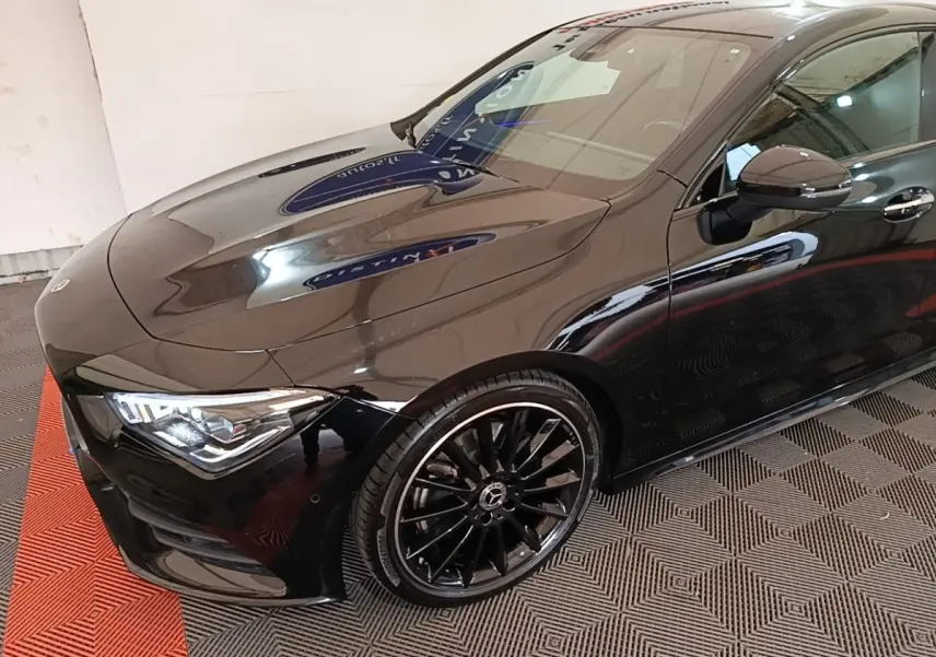Vue 3/4 avant droit d'une Mercedes CLA 200 d AMG Line noire avec jantes alliage noires et phares LED ellipsoïdaux.