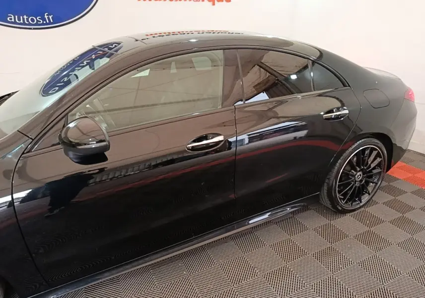 Vue de profil côté gauche d'une Mercedes CLA 200 d AMG Line noire avec jantes alliage noires et poignées chromées.