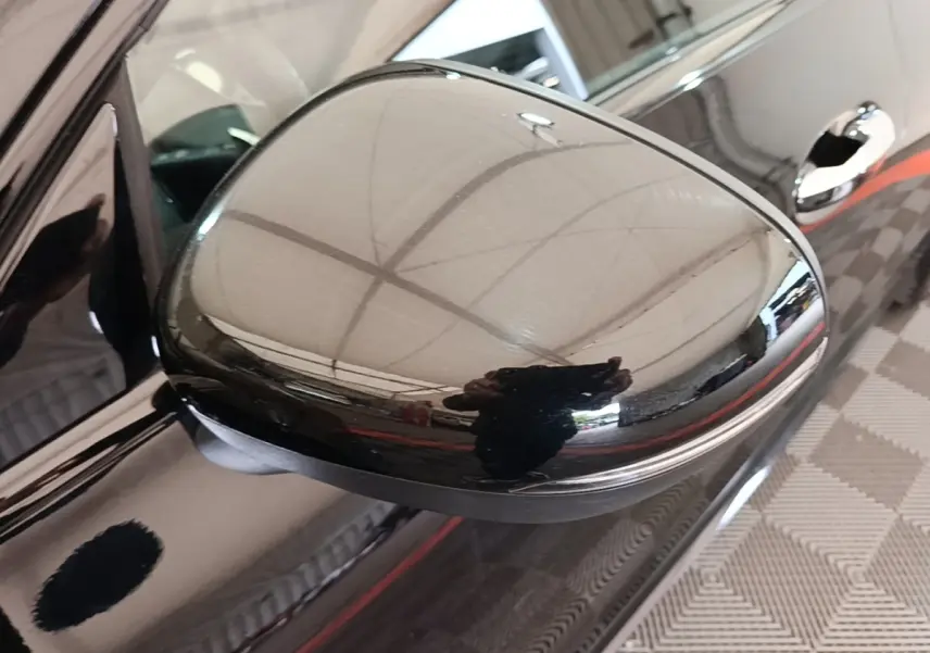 Rétroviseur côté gauche noir brillant d'une Mercedes CLA 200 d AMG Line 2022, avec poignée de porte visible en arrière-plan.