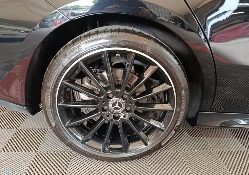 Gros plan sur la roue arrière droite noire avec jante AMG brillante d'une Mercedes CLA 200 d AMG Line noire.