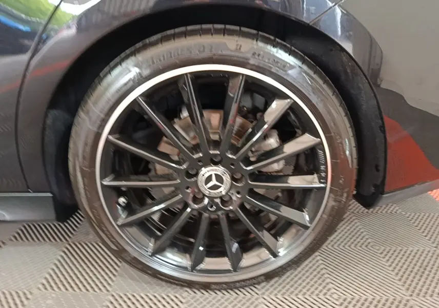 Gros plan sur la jante noire AMG à multiples branches d’une Mercedes CLA 200 d AMG Line noire, côté arrière droit.