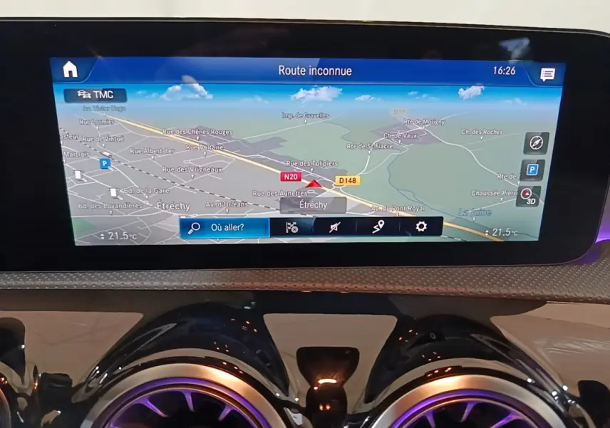 Gros plan sur l'écran tactile de navigation 10,3 pouces et les aérateurs ronds à éclairage violet du tableau de bord d'une Mercedes CLA 200 d AMG Line noire.