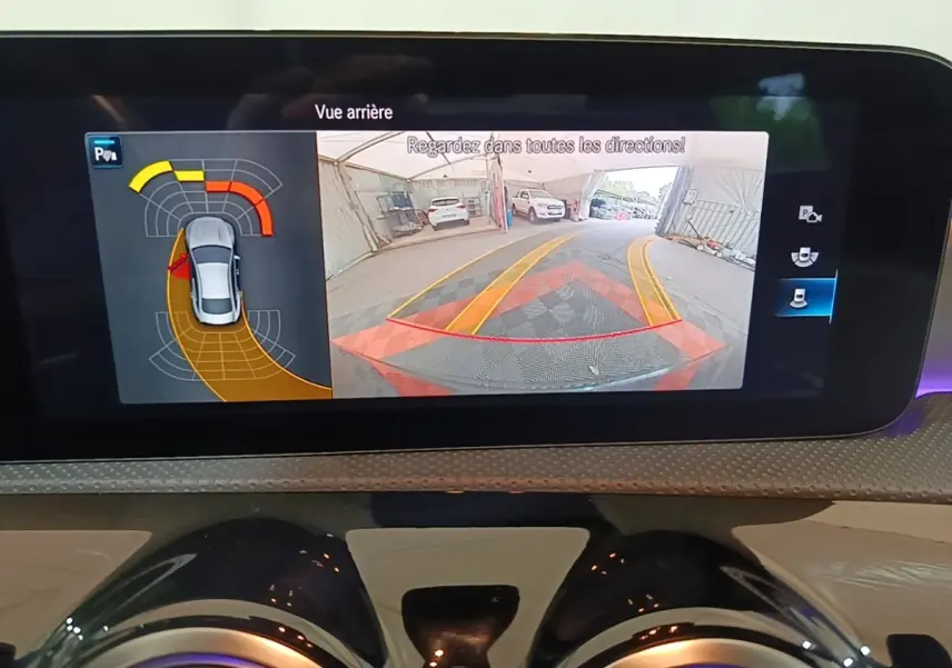 Écran tactile intérieur montrant la caméra de recul et l'aide au stationnement du Mercedes CLA 200 d AMG Line noir.