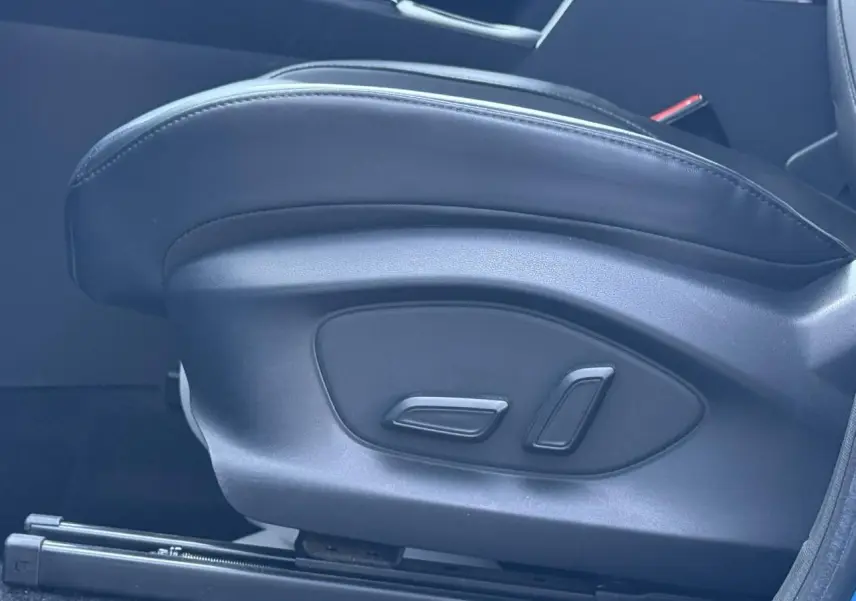 Gros plan sur les commandes de réglage électrique du siège avant en tissu/similicuir noir du MG ZS 1.5 Hybrid+ 197 Luxury 2025.