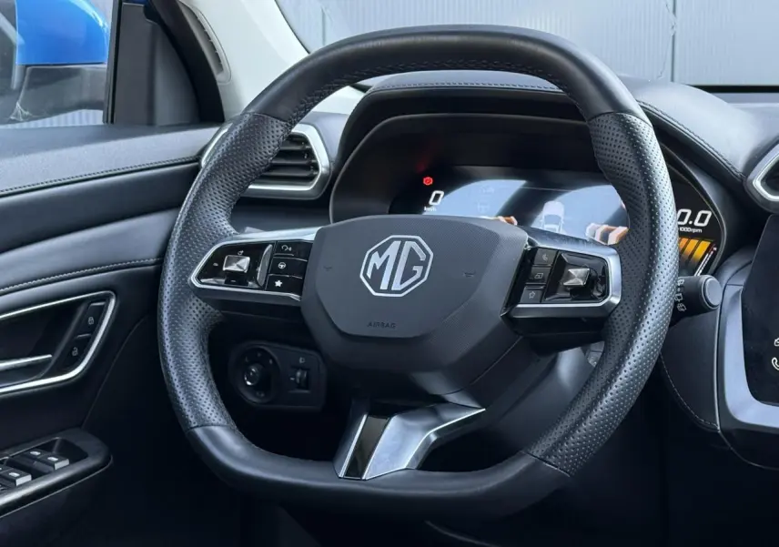 Volant en cuir noir avec logo MG au centre, vue rapprochée de l'intérieur côté conducteur du MG ZS 1.5 Hybrid+ 197 Luxury.