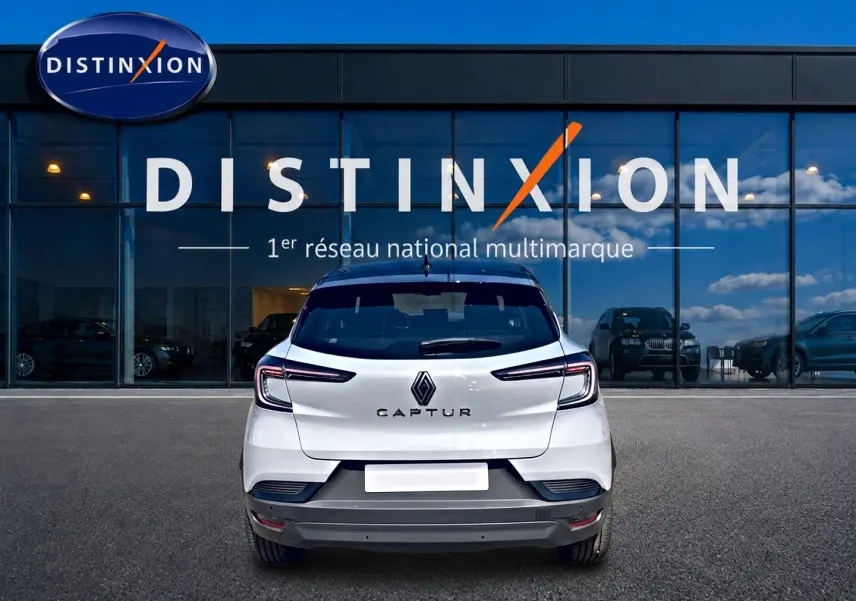 Vue arrière d'un Renault Captur 1.2 TCe 115 Techno blanc avec toit noir, garé devant une vitrine Distinxion.