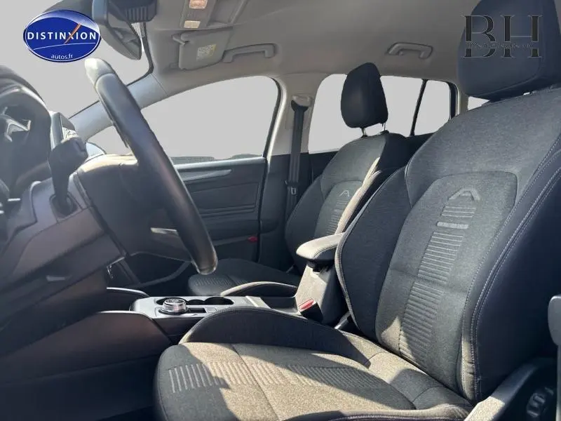 Intérieur avant de la Ford Focus 1.5 EcoBlue 2019, sièges tissu noir avec accoudoir central et volant cuir multifonction.