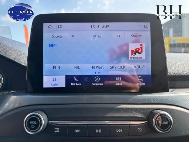 Écran tactile central de la Ford Focus 1.5 EcoBlue 2019 affichant la radio NRJ, avec commandes audio en dessous.