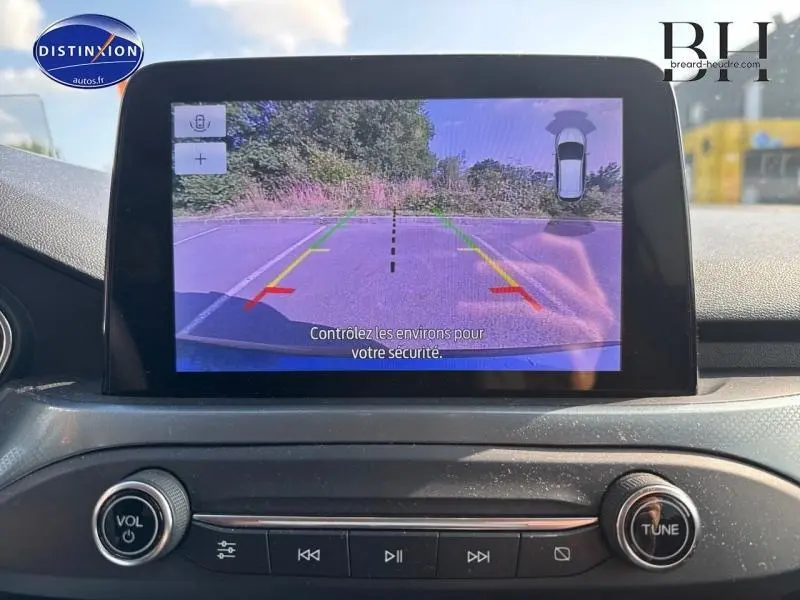 Écran tactile intérieur montrant la caméra de recul avec guidage, tableau de bord noir d'une Ford Focus bleu azur 2019