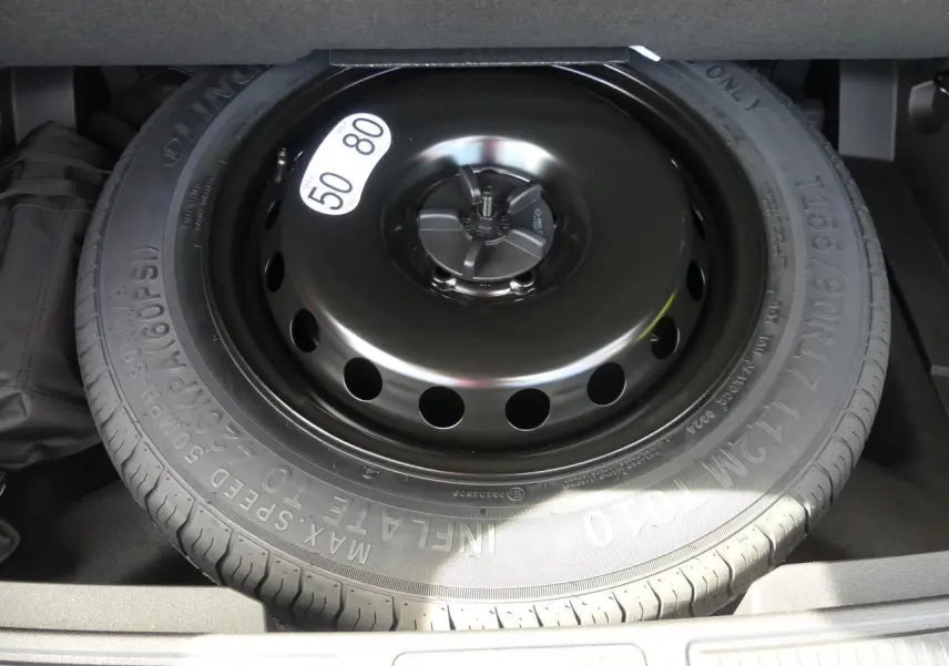 Roue de secours galette noire dans le coffre du Renault Austral gris métallisé 2025, vue en plongée rapprochée.