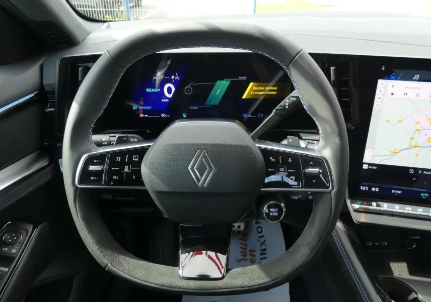 Vue rapprochée du volant Alcantara noir avec surpiqûres bleues du Renault Austral 2025, tableau de bord digital et écran tactile.