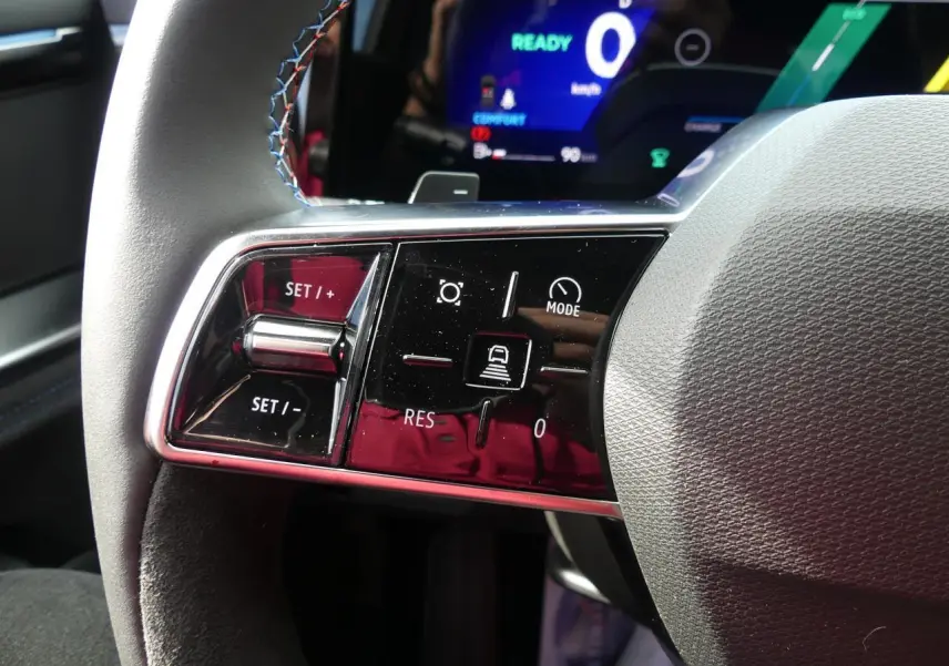 Gros plan sur le volant gris clair du Renault Austral 2025 avec commandes de régulateur de vitesse et affichage digital bleu.