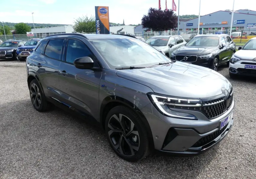 Renault Austral gris métallisé en 3/4 avant droit, avec calandre à damier ice black et jantes alliage 20 pouces.