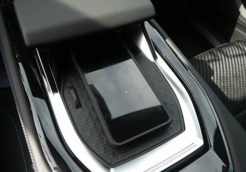 Gros plan sur la console centrale noire brillante du Renault Austral 2025 avec chargeur smartphone par induction et sellerie tissu Alcantara.