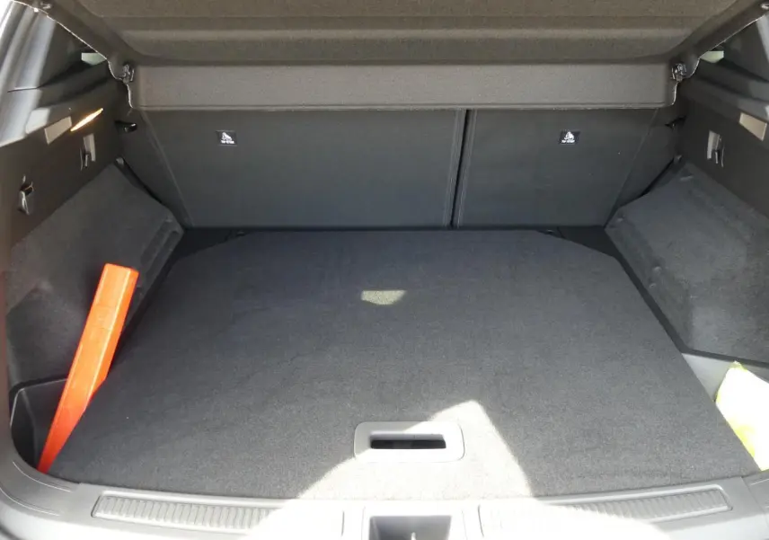 Coffre ouvert vu de l'arrière du Renault Austral gris métallisé, avec tapis de sol et triangle de signalisation rouge.