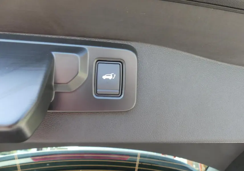 Bouton d'ouverture mains-libres du hayon sur le gris métallisé Renault Austral 2025, vue intérieure du coffre.