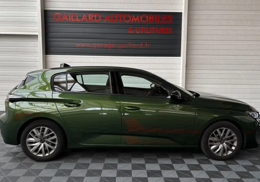 Profil latéral droit d'une Peugeot 308 vert foncé garée devant un mur blanc avec logo rouge Gaillard Automobiles.