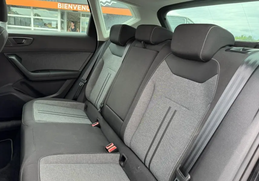 Vue intérieure arrière du SEAT Ateca 2023, sellerie textile gris et noir avec appuie-têtes et ceintures visibles.