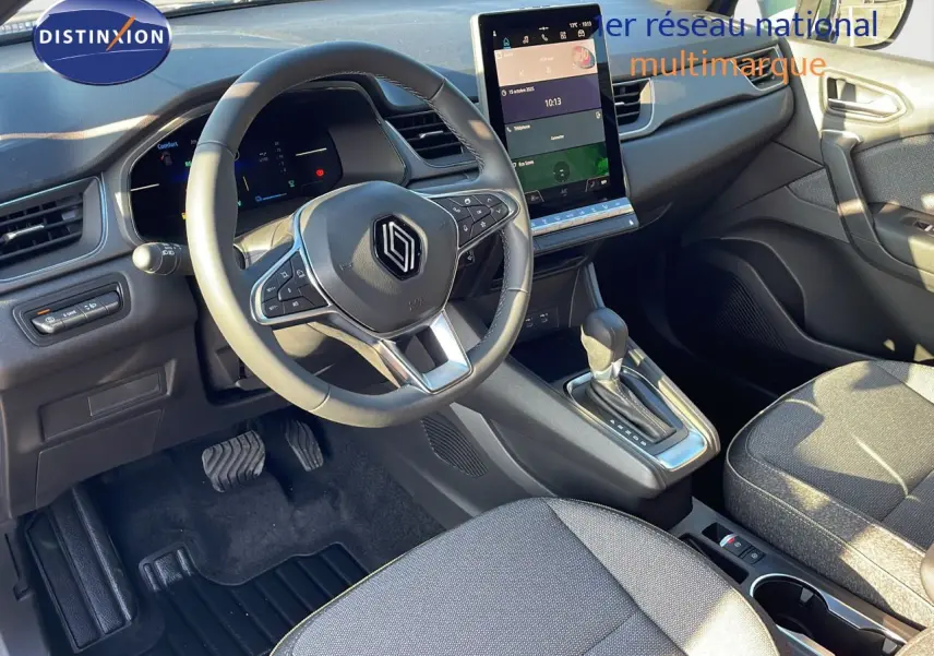 Vue intérieure côté conducteur du Renault Captur E-Tech Hybrid 2025, avec volant multifonction et écran tactile vertical.