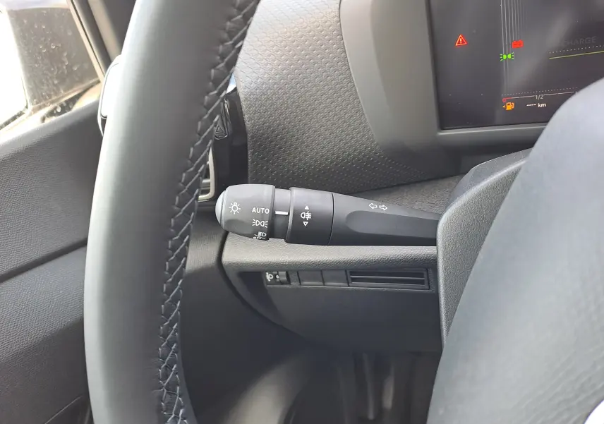 Gros plan sur la manette des feux à gauche du volant dans l'habitacle d'une Citroën C4 hybride 2025.