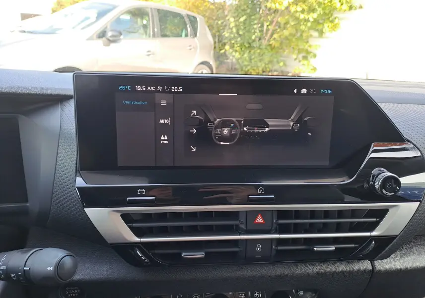 Tableau de bord de la Citroën C4 hybride 2025 avec écran tactile central et commandes de climatisation visibles.
