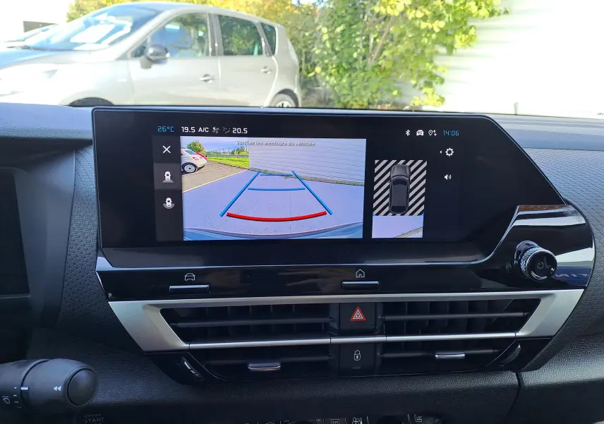 Écran central du tableau de bord d'une Citroën C4 hybride 2025 montrant la caméra de recul et les capteurs de stationnement.