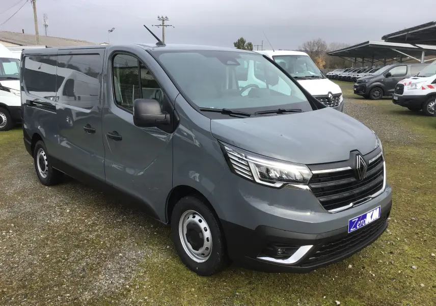 Renault Trafic Fourgon gris urbain en 3/4 avant droit, avec calandre noire et phares LED distinctifs.