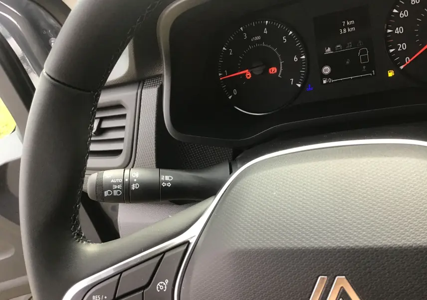 Vue rapprochée du volant et du tableau de bord du Renault Trafic Fourgon gris urbain, affichant les compteurs et commandes.