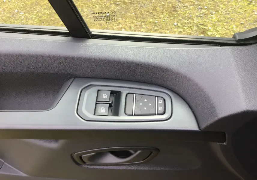 Détail des commandes des vitres et rétroviseurs sur la porte côté conducteur du Renault Trafic Fourgon gris urbain.