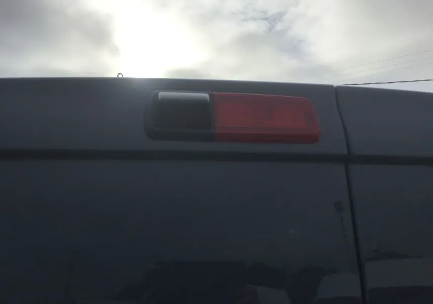 Gros plan sur le feu arrière droit du Renault Trafic Fourgon gris urbain, vue de l'arrière sous un ciel nuageux.