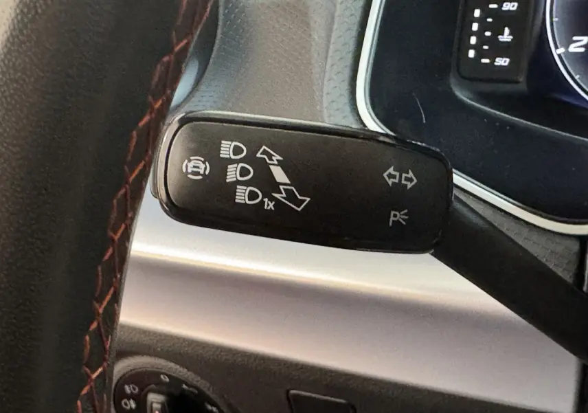 Gros plan sur la commande de clignotants noire et volant cuir rouge de la SEAT IBIZA 2024 côté gauche.