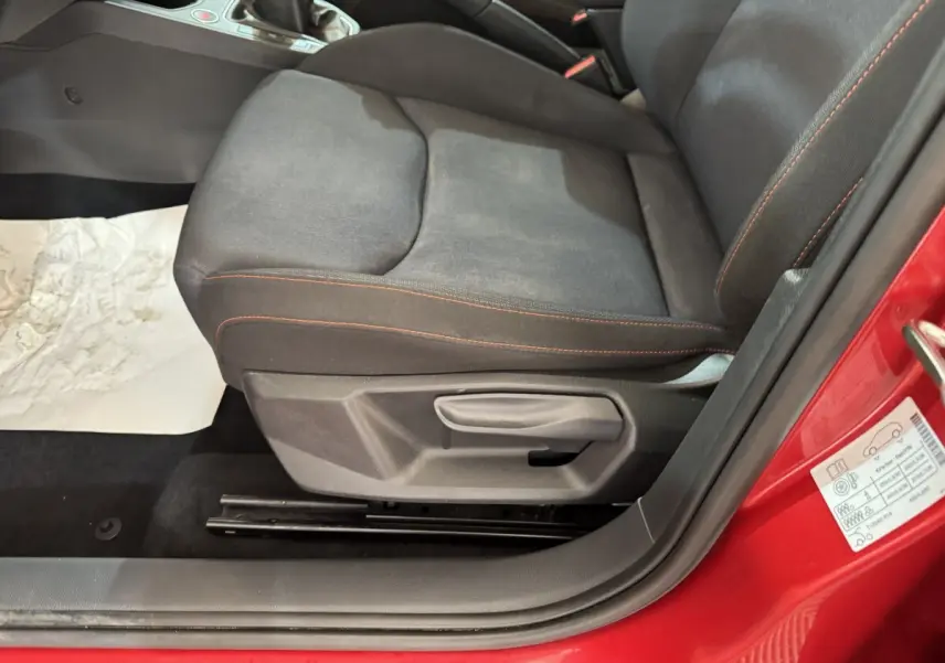Gros plan sur le siège conducteur noir avec surpiqûres rouges d'une SEAT IBIZA rouge 2024, côté gauche ouvert.