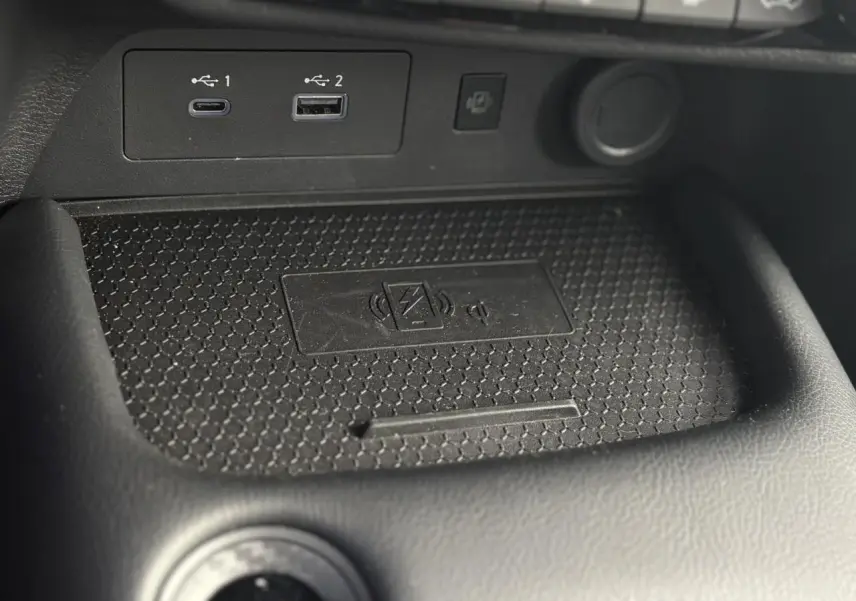Gros plan sur la zone de recharge sans fil et ports USB du Nissan Juke 2025 gris foncé, intérieur noir.