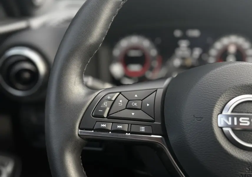 Gros plan sur le volant en cuir noir du Nissan Juke 2025, avec commandes multifonctions visibles côté gauche.