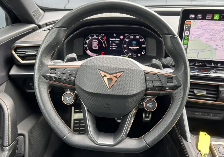 Vue rapprochée du volant cuir perforé noir avec logo CUPRA cuivre et tableau de bord digital du Formentor gris magnétique.