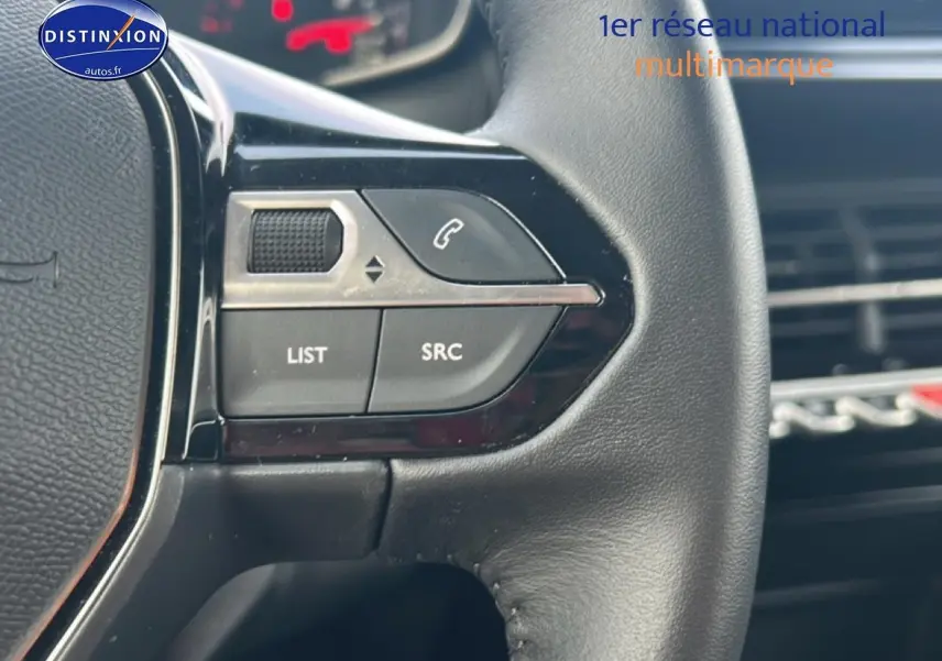 Gros plan sur les commandes audio au volant noir de la Peugeot 208 1.2 100 style, intérieur moderne et finition soignée.