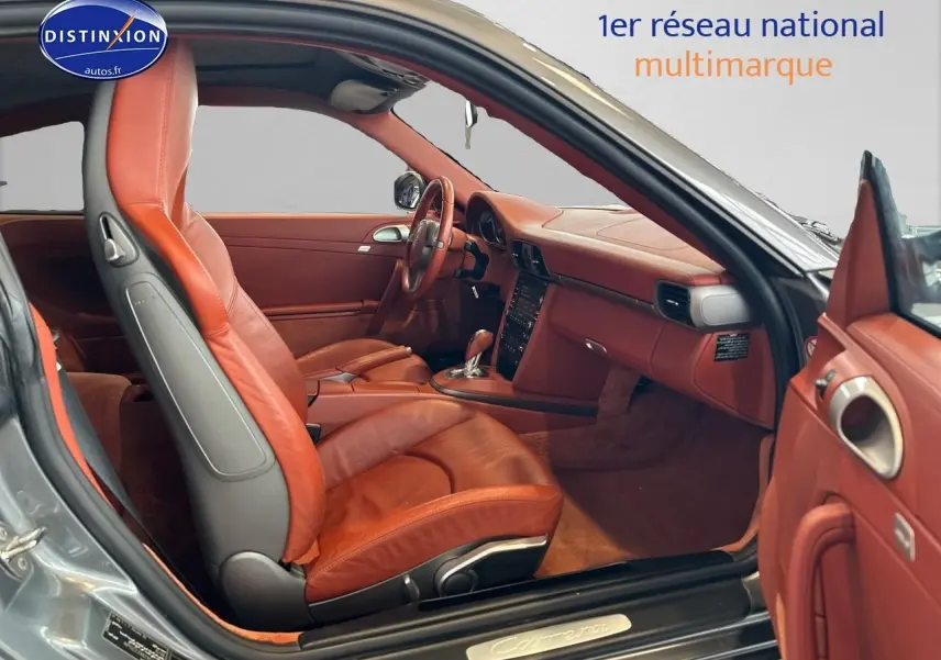 Intérieur cuir marron vu côté conducteur d'une Porsche 911 (997) Carrera PDK gris, avec tableau de bord et sièges sport visibles.