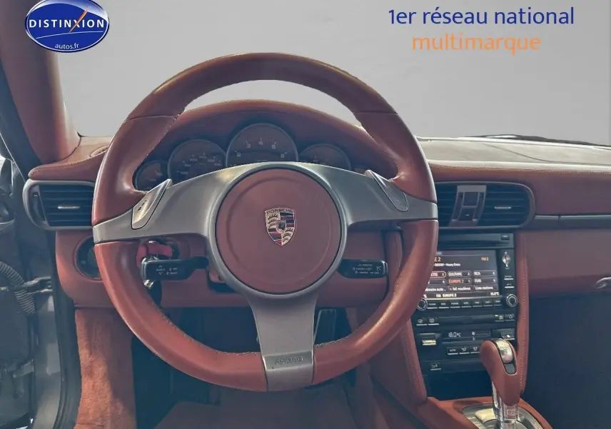 Intérieur d'une Porsche 911 (997) carrera pdk 2009, vue centrée sur le volant cuir marron et la console centrale.