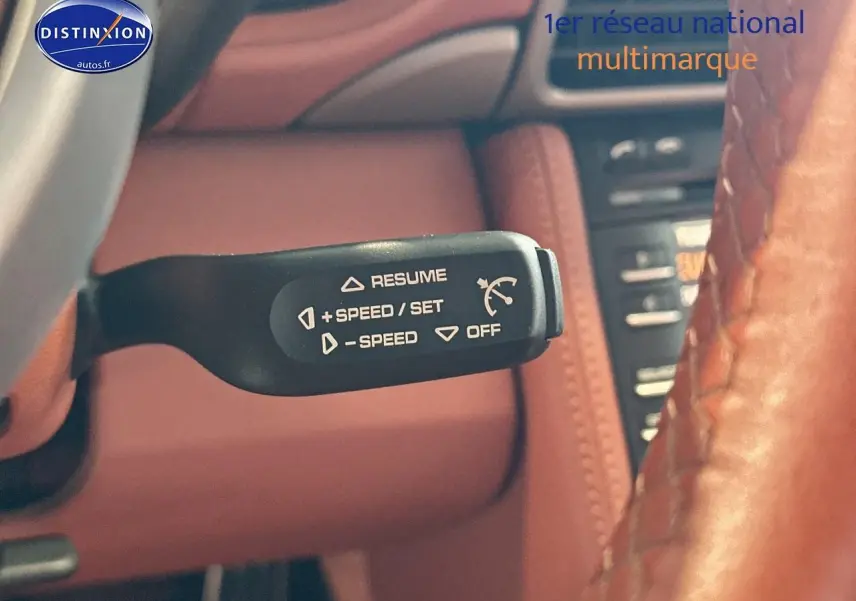 Levier de régulateur de vitesse noir sur fond de cuir marron à l'intérieur d'une Porsche 911 gris 997 carrera pdk.