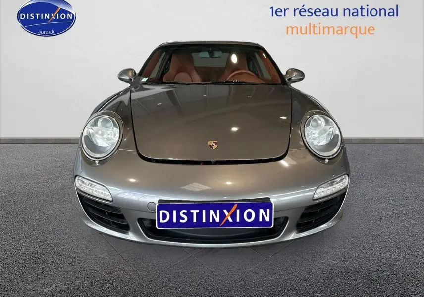 Vue frontale d'une Porsche 911 (997) Carrera PDK gris métallisé avec phares ronds et intérieur cuir marron visible.
