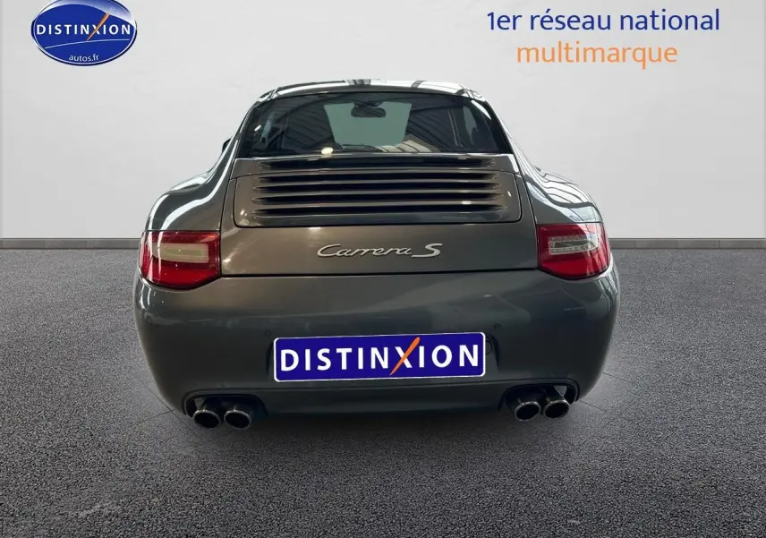 Vue arrière d'une Porsche 911 (997) Carrera S gris métallisé avec double sortie d'échappement et feux rouges.