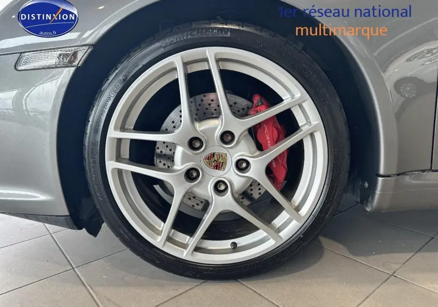 Gros plan sur la jante alu argentée avec étrier de frein rouge d'une Porsche 911 (997) carrera pdk gris côté avant droit.