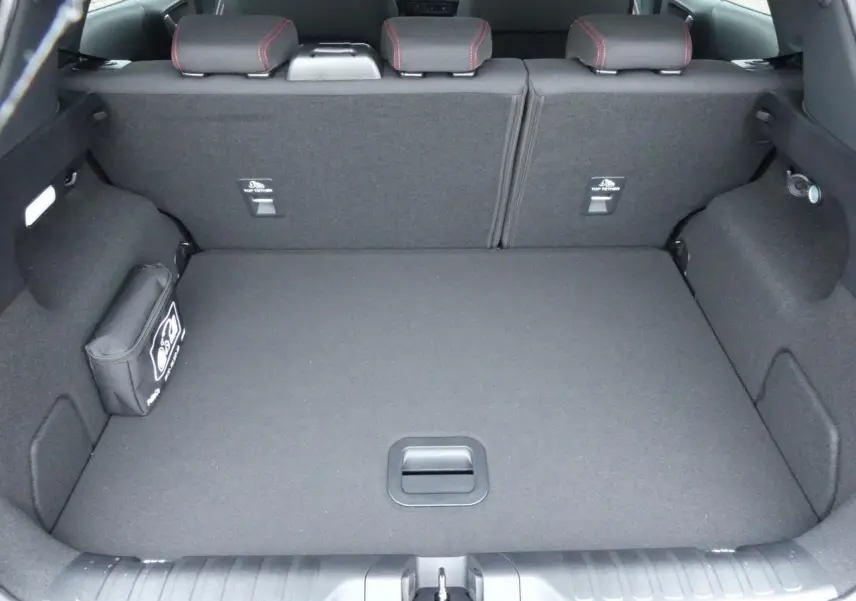 Coffre ouvert vu de l'arrière d'un Ford Puma 2025 gris métallisé, avec tapis de coffre plat et rangement latéral.